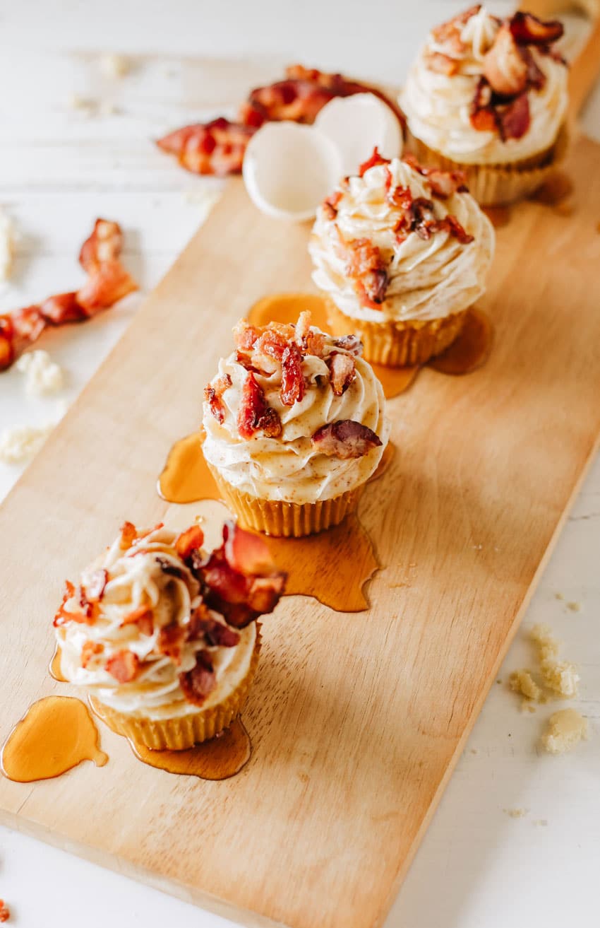 maple bacon pancake muffins drizzled with syrup on a wooden cutting board