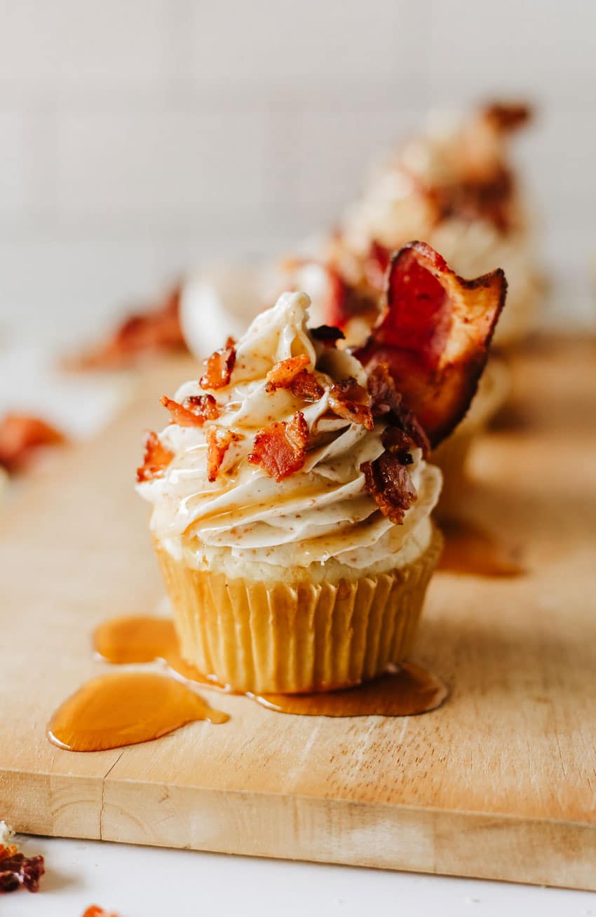 maple bacon pancake muffins drizzled with syrup on a wooden cutting board