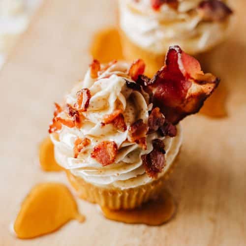 maple bacon pancake muffins drizzled with syrup on a wooden cutting board