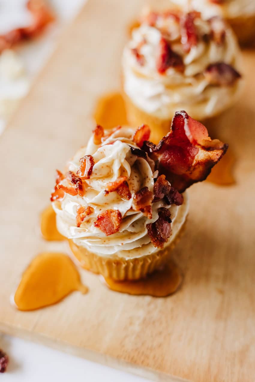 Maple Bacon Pancake Muffins maple bacon pancake muffins drizzled with syrup on a wooden cutting board