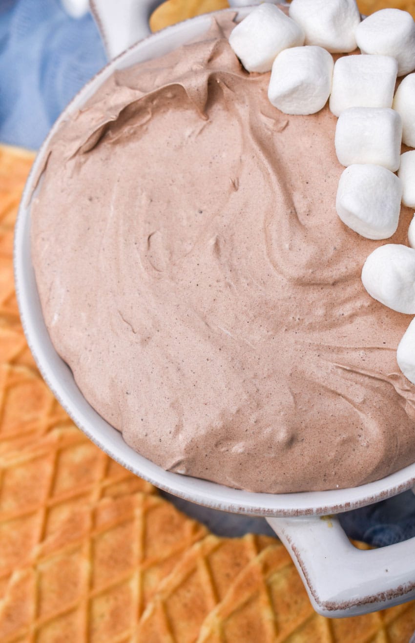 a white bowl filled with hot cocoa dip topped with mini marshmallows