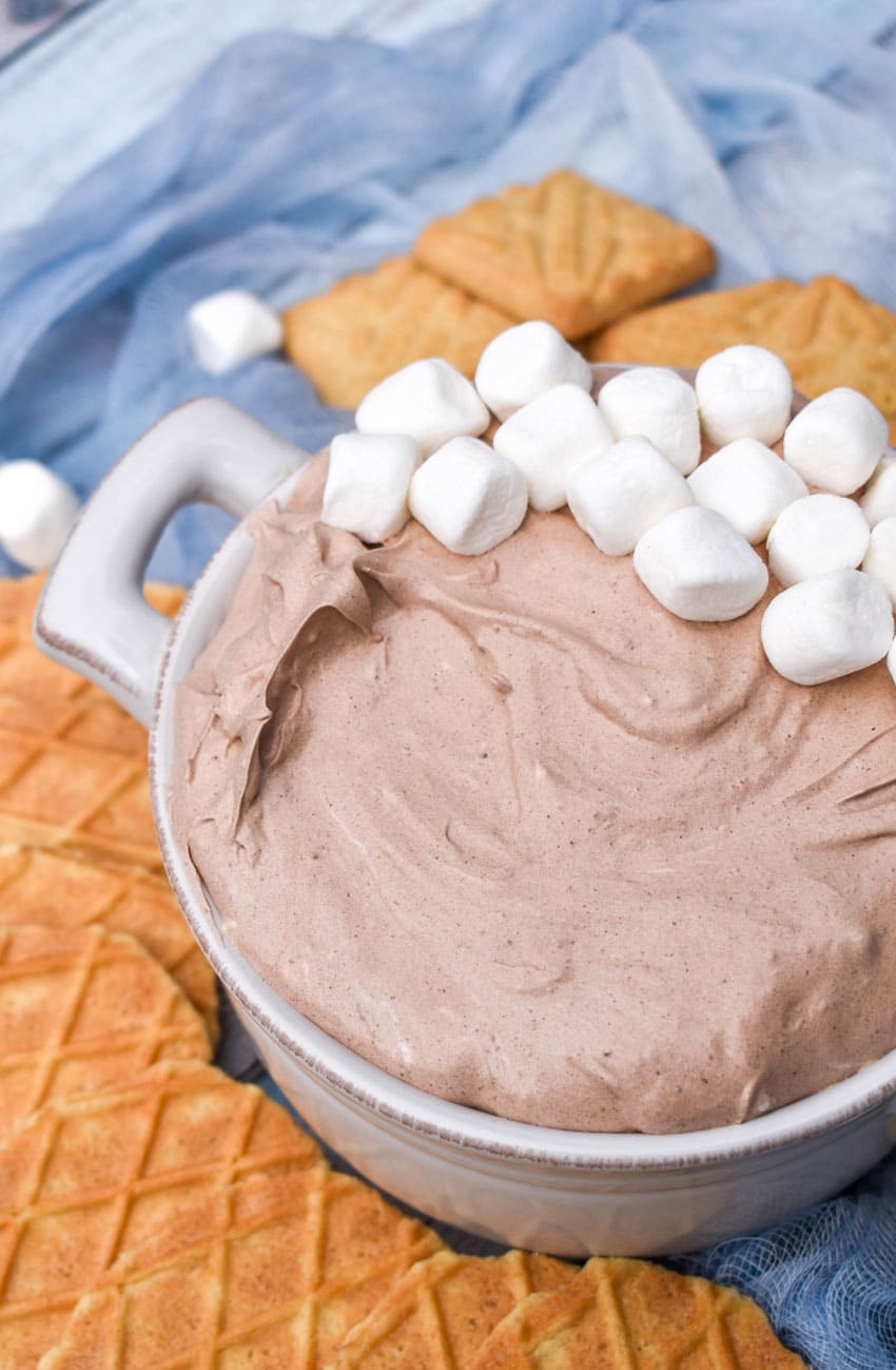 a white bowl filled with hot cocoa dip topped with mini marshmallows