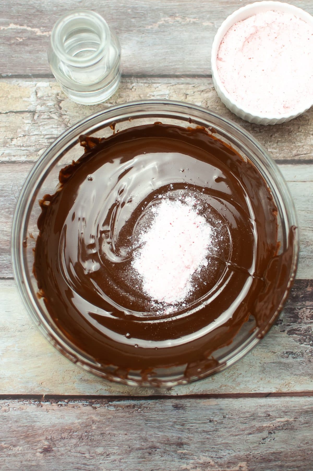 melted chocolate chips with crushed peppermints in a glass mixing bowl
