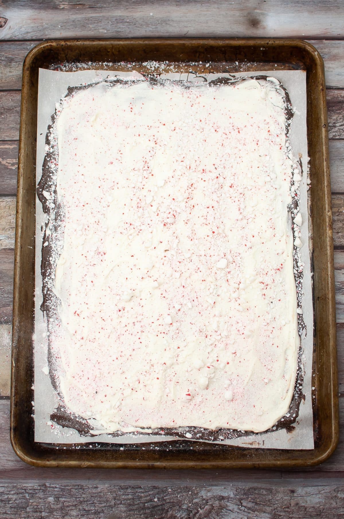 homemade peppermint bark hardening on a parchment paper lined metal baking sheet
