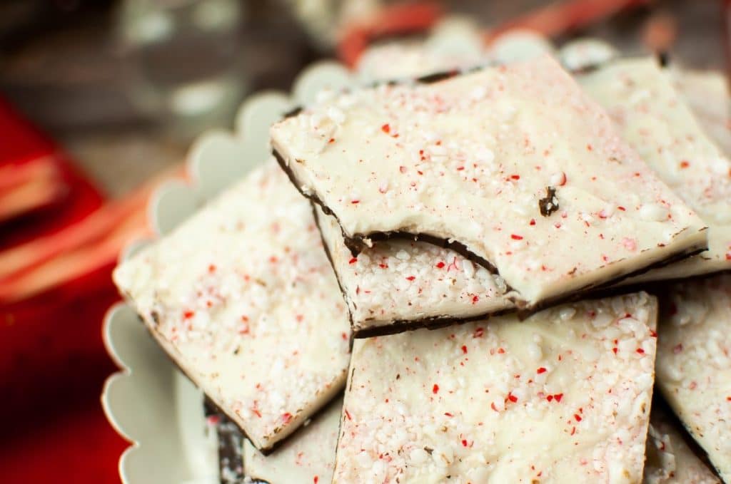 squares of homemade peppermint bark stacked on a white cake stand