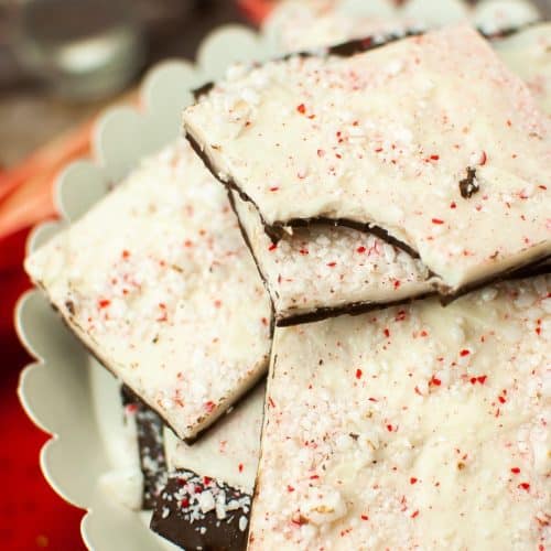 squares of homemade peppermint bark stacked on a white cake stand