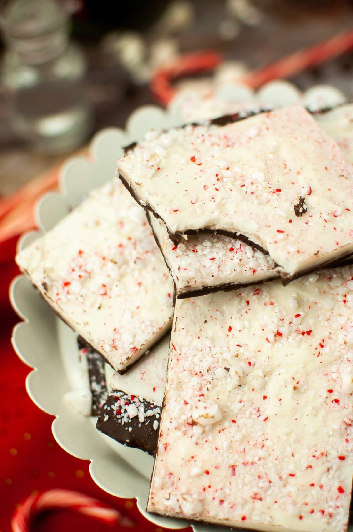 Peppermint Bark squares of homemade peppermint bark stacked on a white cake stand