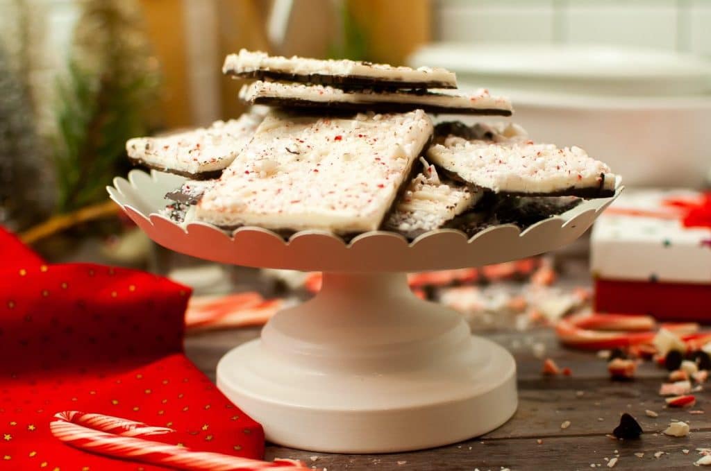 squares of homemade peppermint bark stacked on a white cake stand