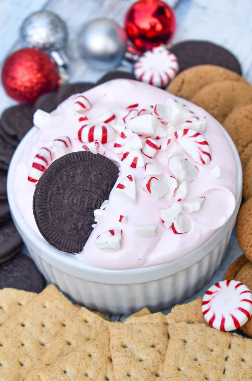 an oreo resting in a bowl of peppermint cheesecake dip