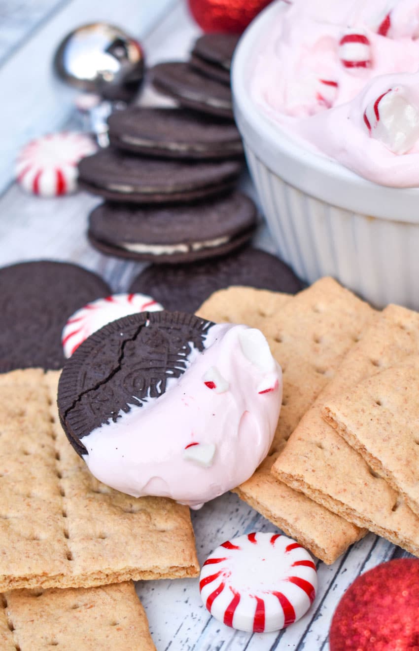 an oreo topped with peppermint cheesecake dip resting on a pile of graham crackers