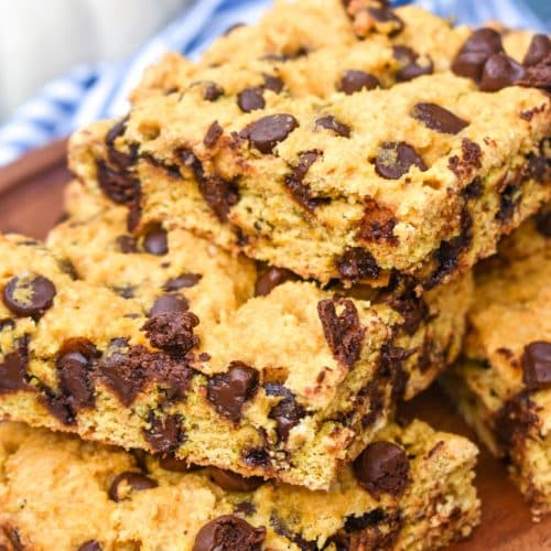 a stack of pumpkin chocolate chip cookie bar squares on a wooden cake stand