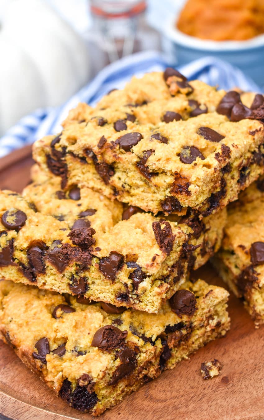 Pumpkin Chocolate Chip Cookie Bars a stack of pumpkin chocolate chip cookie bar squares on a wooden cake stand