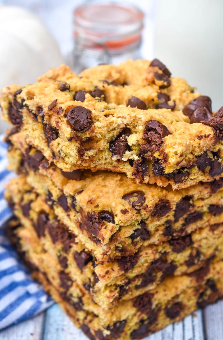 a stack of pumpkin chocolate chip cookie bar squares on a wooden cake stand