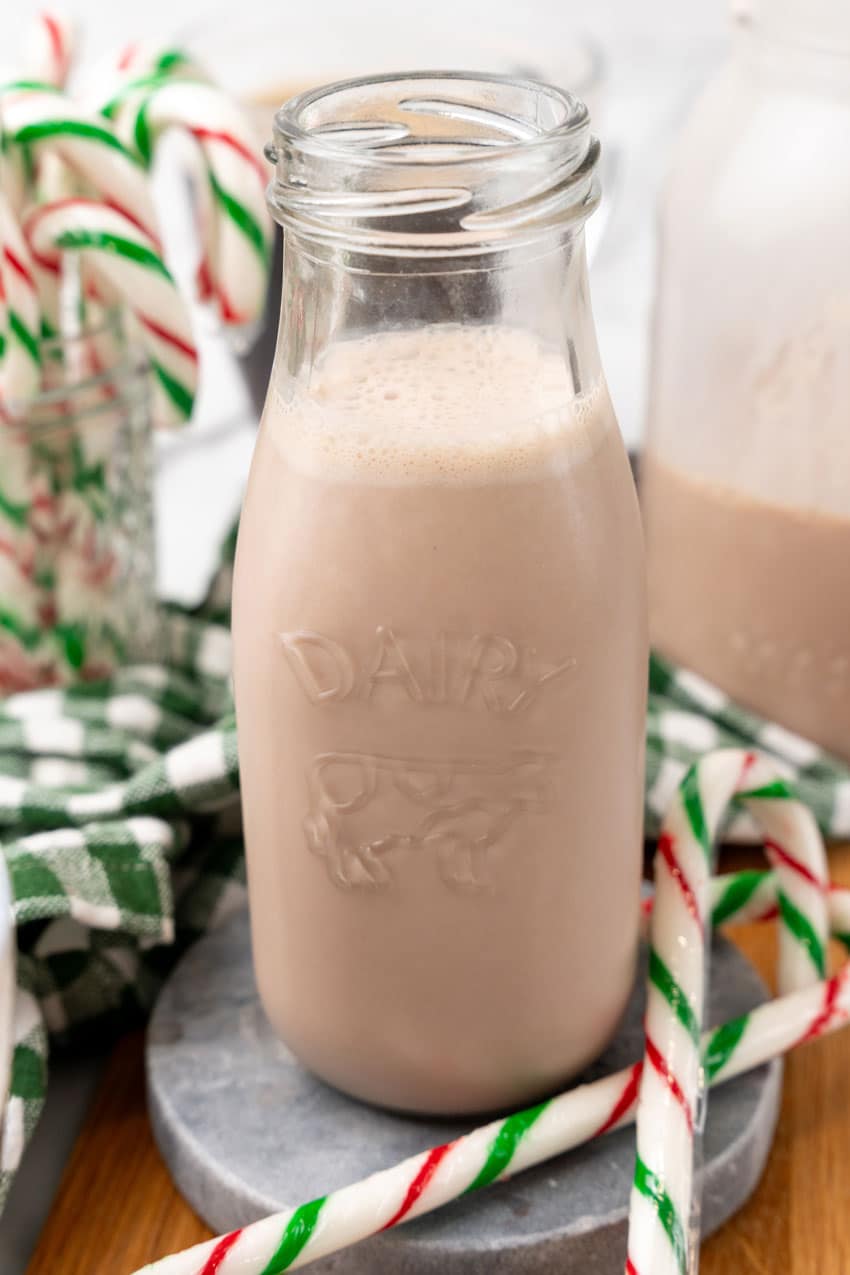 homemade peppermint patty coffee creamer in a small glass jar surrounded by candy canes