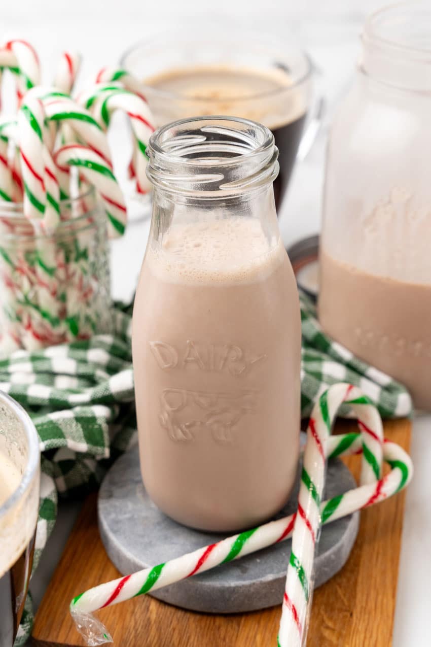 homemade peppermint coffee creamer in a small glass jar surrounded by candy canes