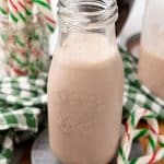 homemade peppermint coffee creamer in a small glass jar surrounded by candy canes