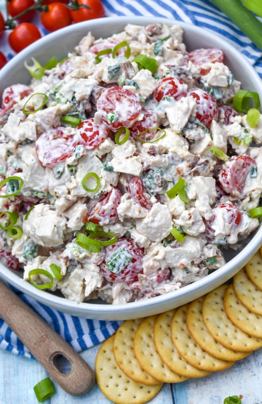 blt chicken salad in a large serving bowl with cherry tomatoes and green onions on the side
