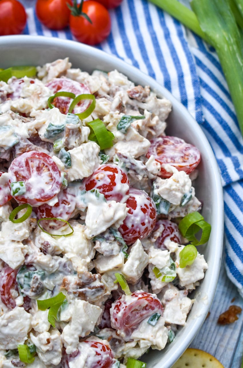 blt chicken salad in a large serving bowl with cherry tomatoes and green onions on the side
