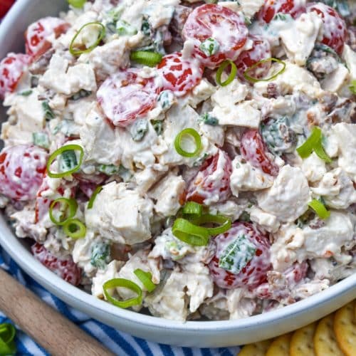 blt chicken salad in a large serving bowl with cherry tomatoes and green onions on the side