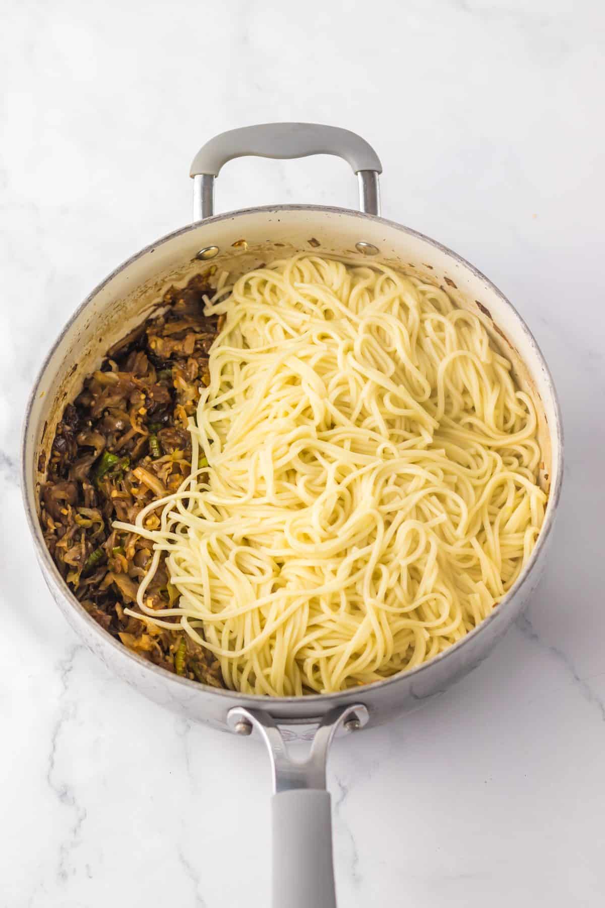 chinese chow mein veggies and sauce with cooked lo mein noodles in a large gray pot
