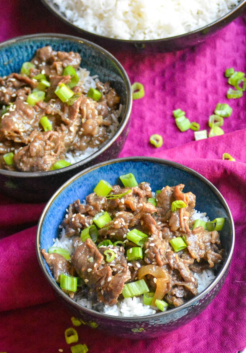 easy beef bulgogi recipe served over steamed white rice in two small blue bowls