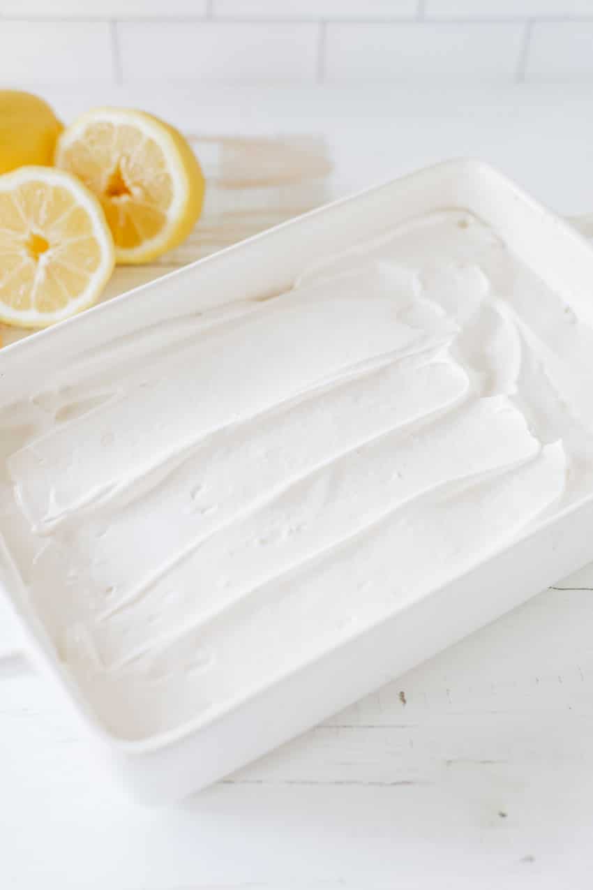 lemon flavored whipped topping spread out in an even layer in a white baking dish