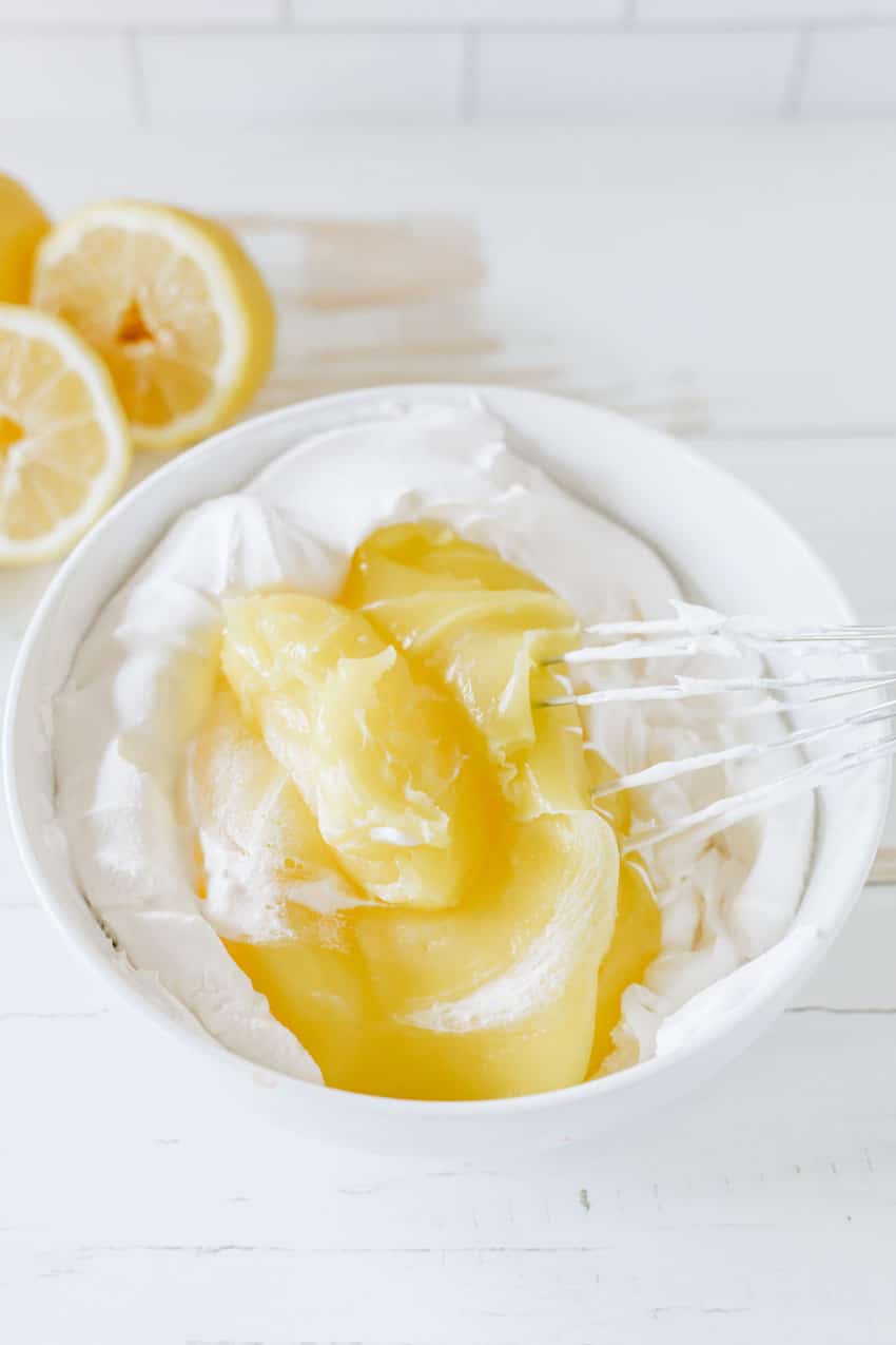 lemon pie filling being stirred into thawed whipped topping in a small white bowl