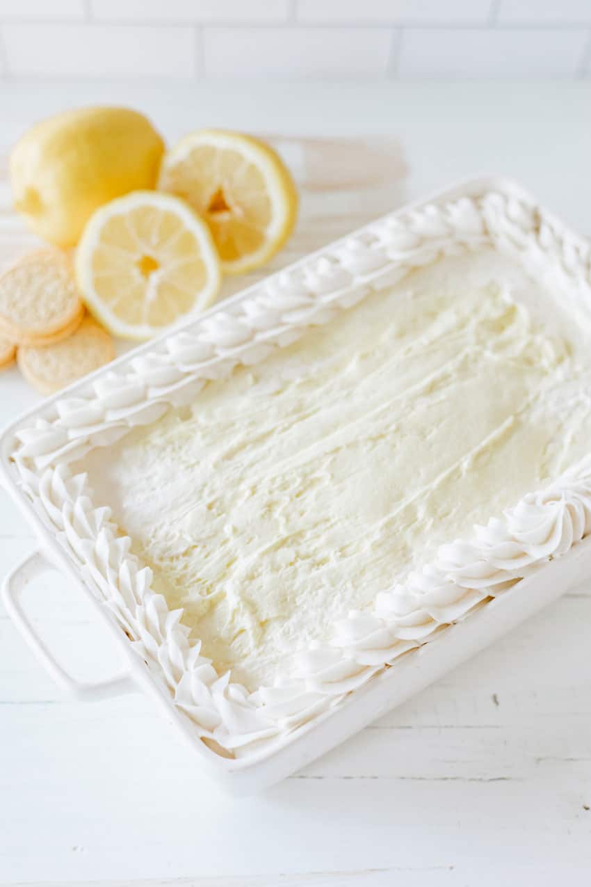 lemon oreo lasagna in a white baking dish topped with dollops of white frosting