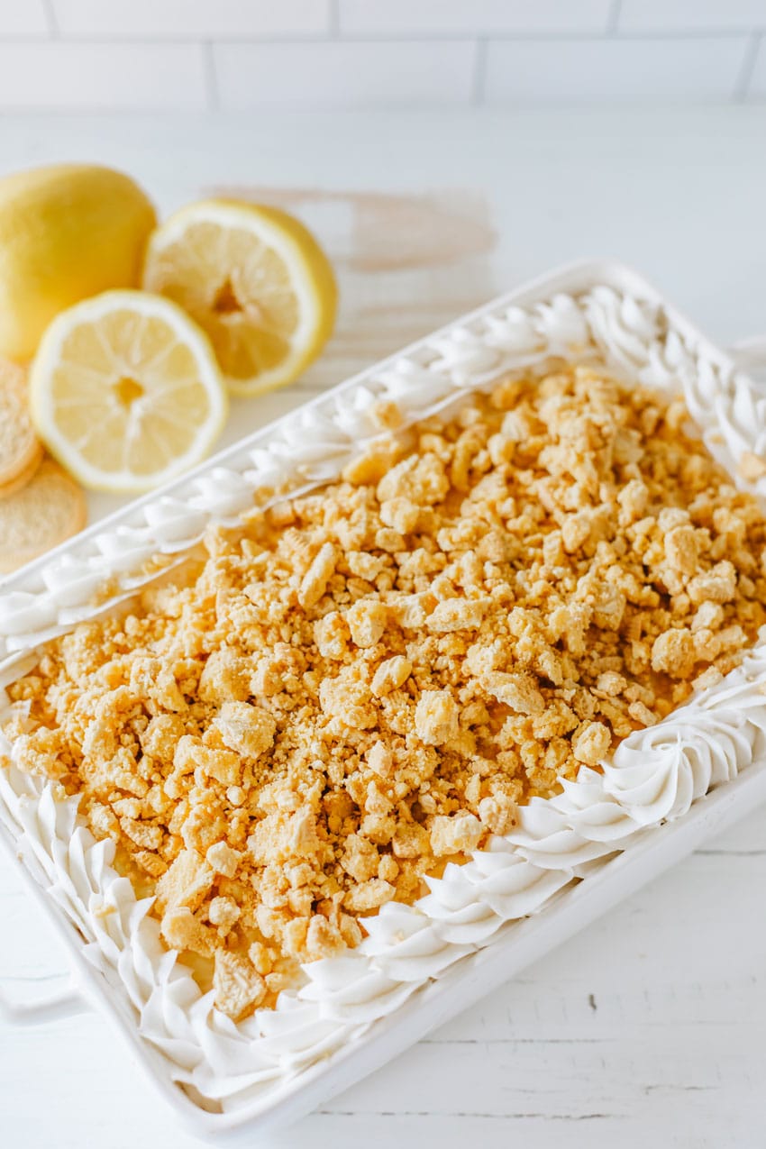 lemon oreo lasagna in a white baking dish topped with dollops of white frosting