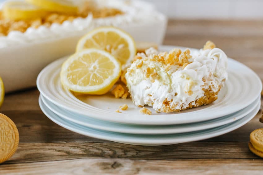 a scoop of lemon oreo lasagna on a white plate with fresh lemon on the side