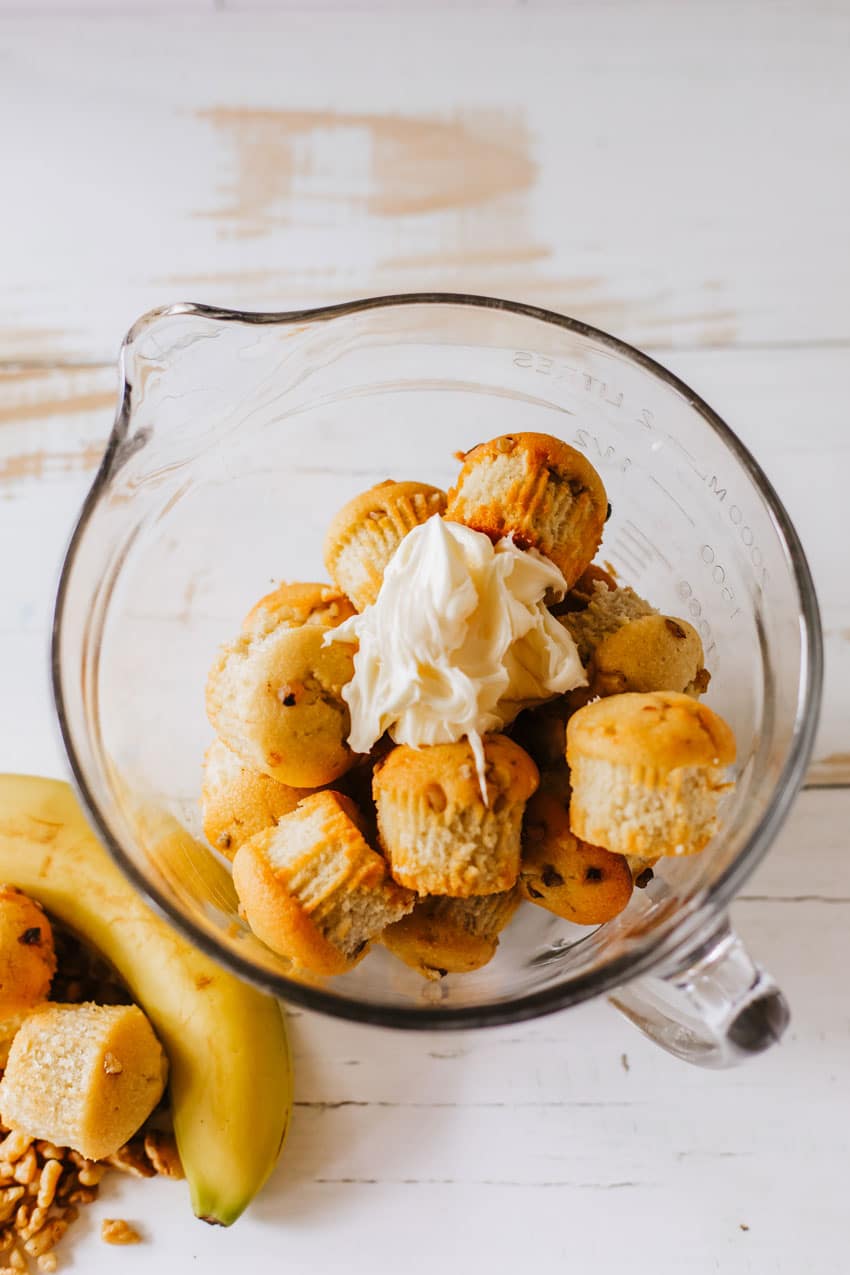 banana bread muffins and cream cheese frosting in a glass mixing bowl on a wooden table