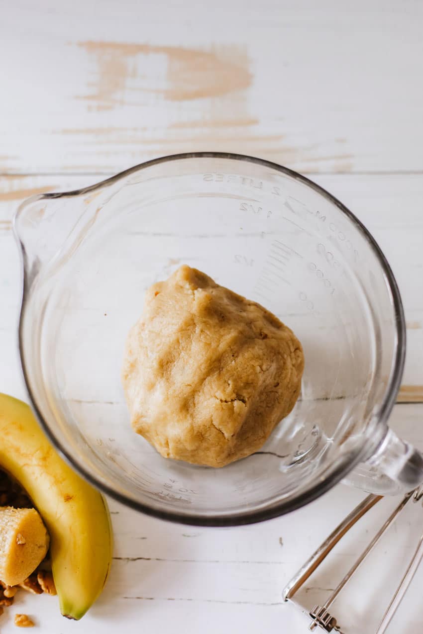 banana bread cake ball dough in a glass mixing bowl on a wooden counter