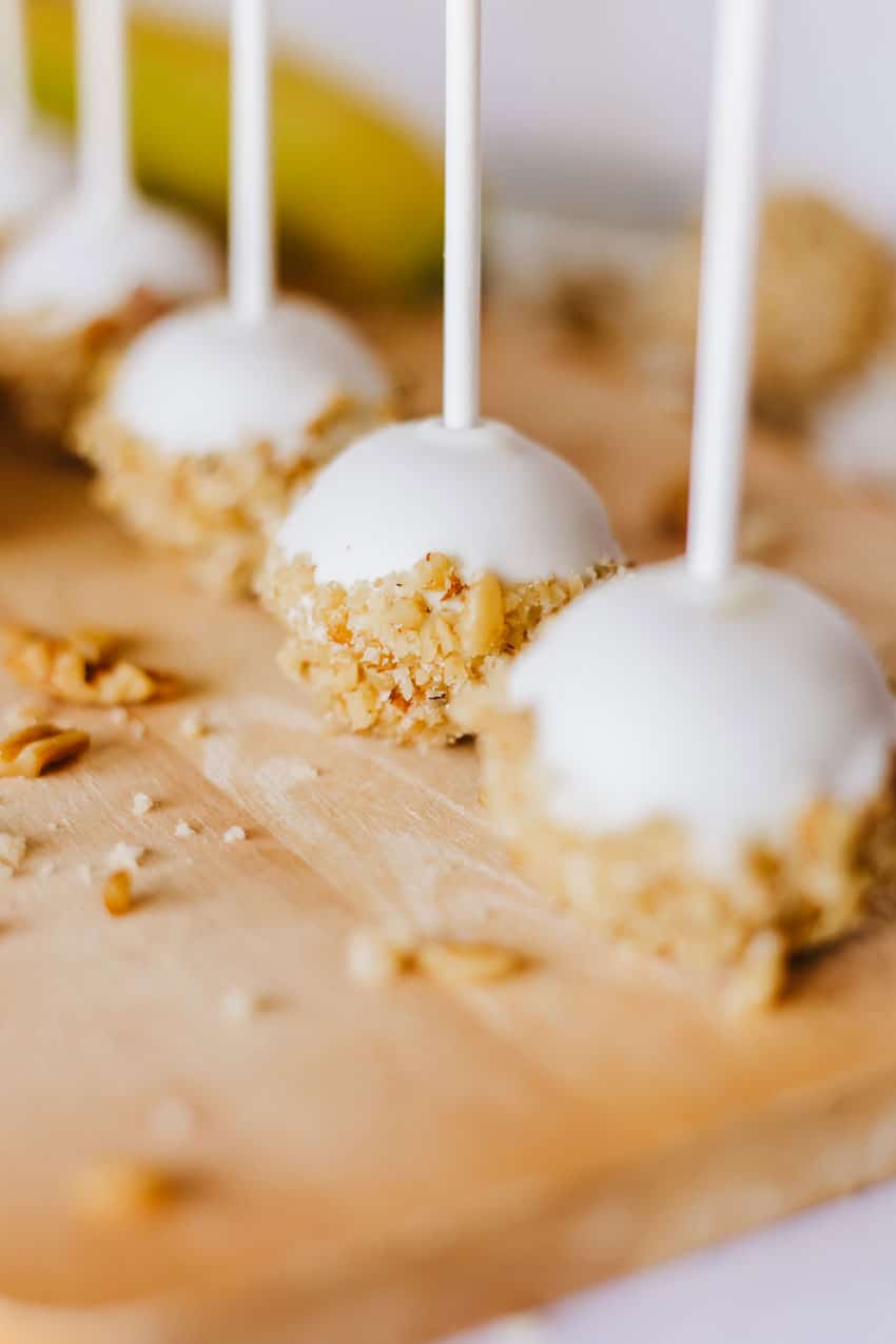 a close up of banana bread cake pops on a wooden cutting board
