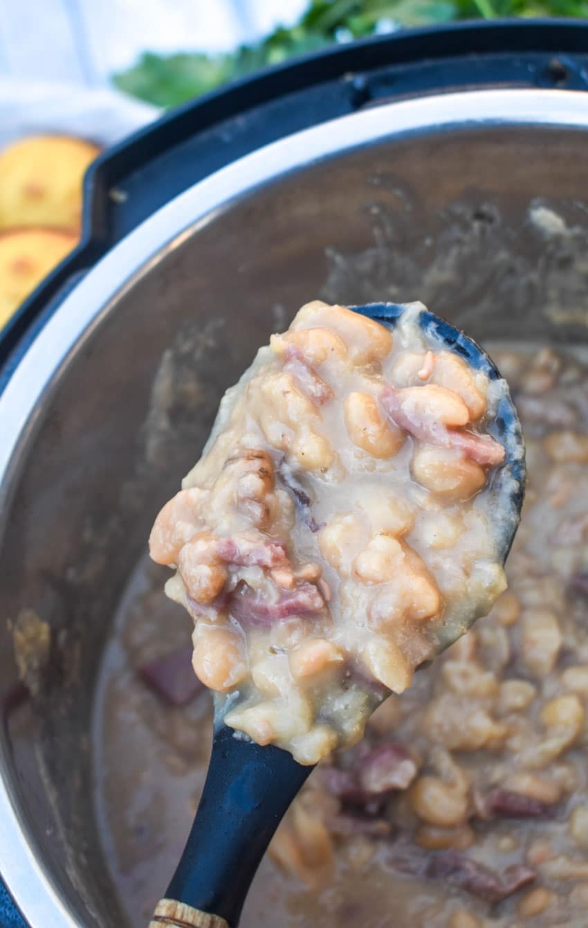 a black spoon scooping ham and beans out of an instant pot
