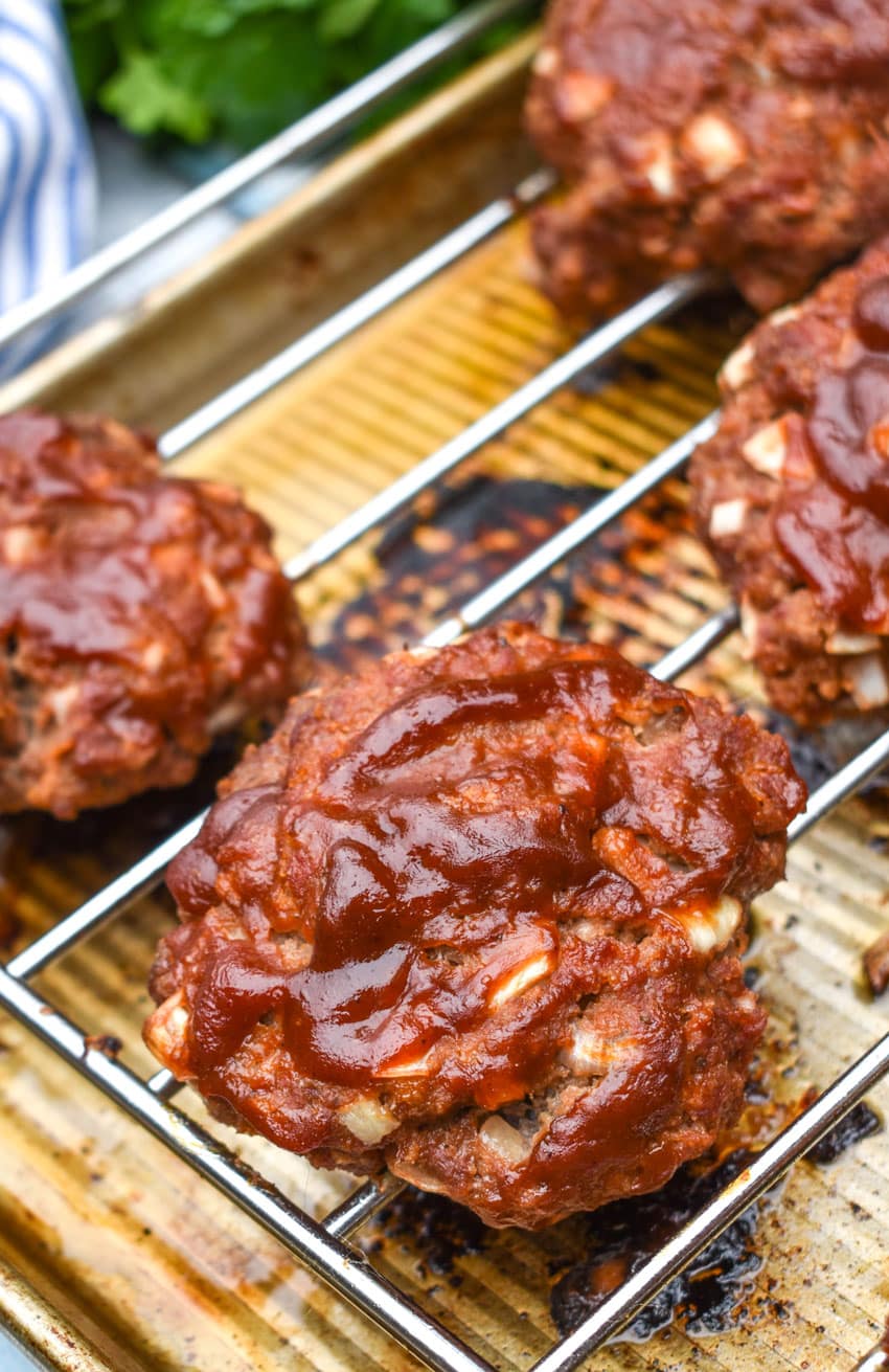 baked glazed meatloaf burgers resting on a wire rack above a rimmed baking sheet