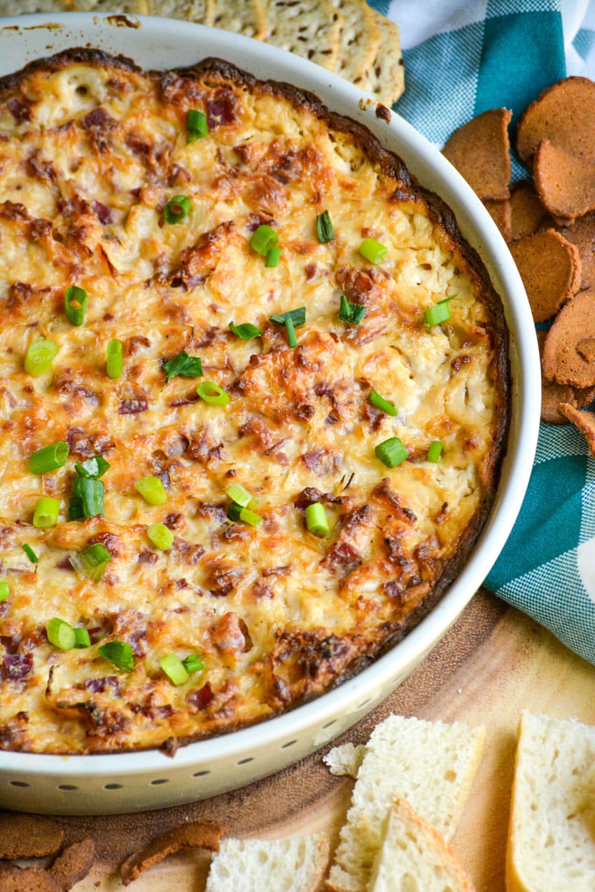 baked reuben dip topped with sliced green onions in a ceramic baking dish