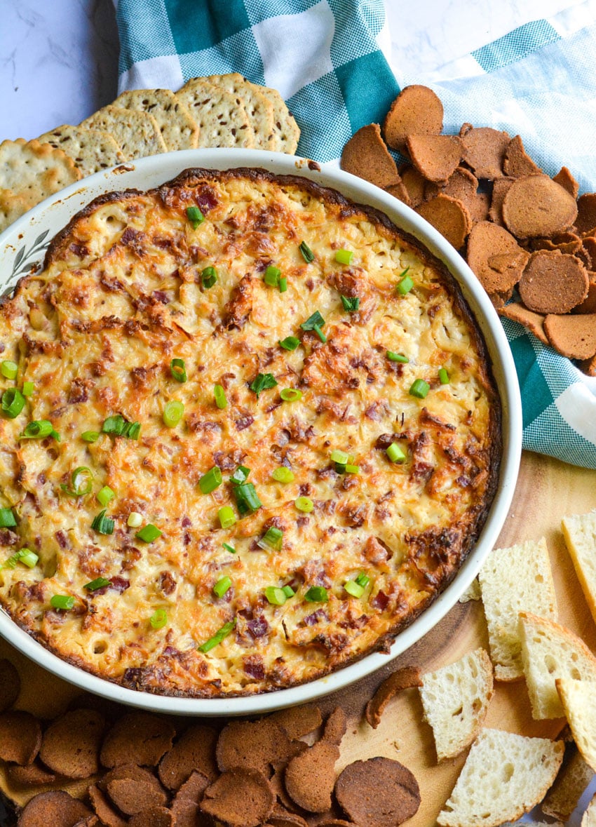 baked reuben dip topped with sliced green onions in a ceramic baking dish