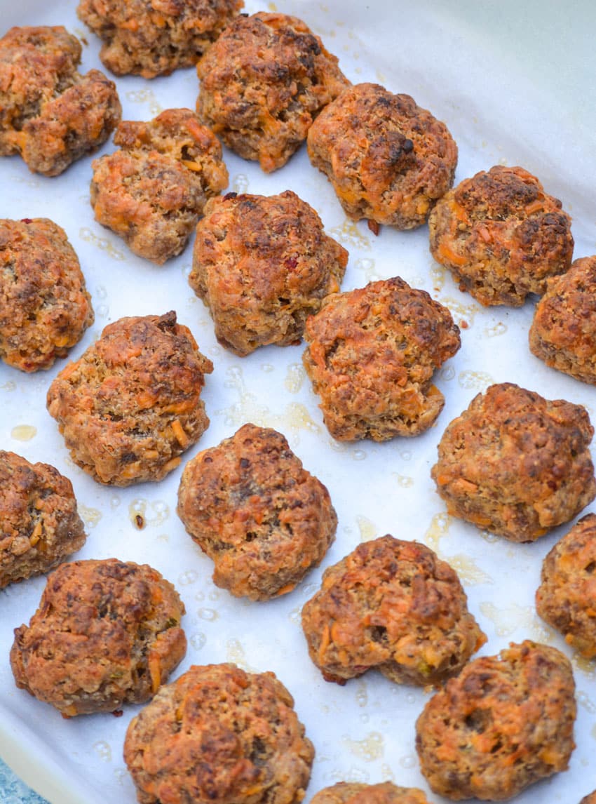 spicy pimento cheese sausage balls arranged in rows on a parchment paper lined rimmed baking sheet