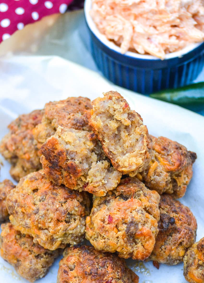 spicy pimento cheese sausage balls piled on a parchment paper lined platter