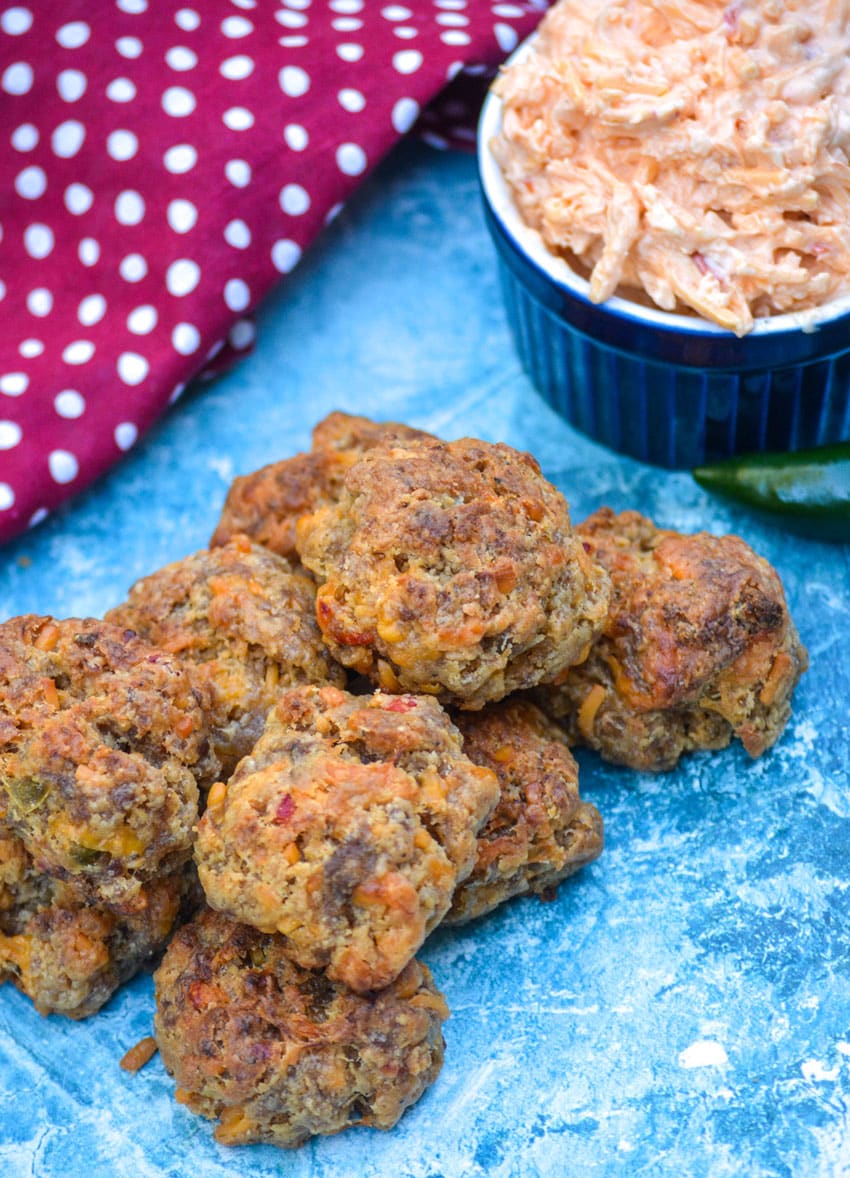 spicy pimento cheese sausage balls piled on a parchment paper lined platter