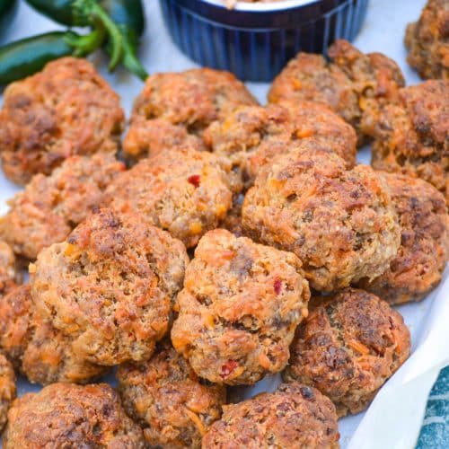 spicy pimento cheese sausage balls piled on a parchment paper lined platter