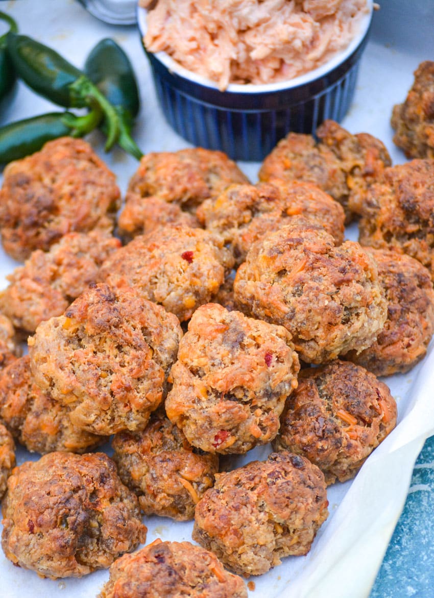 spicy pimento cheese sausage balls piled on a parchment paper lined platter
