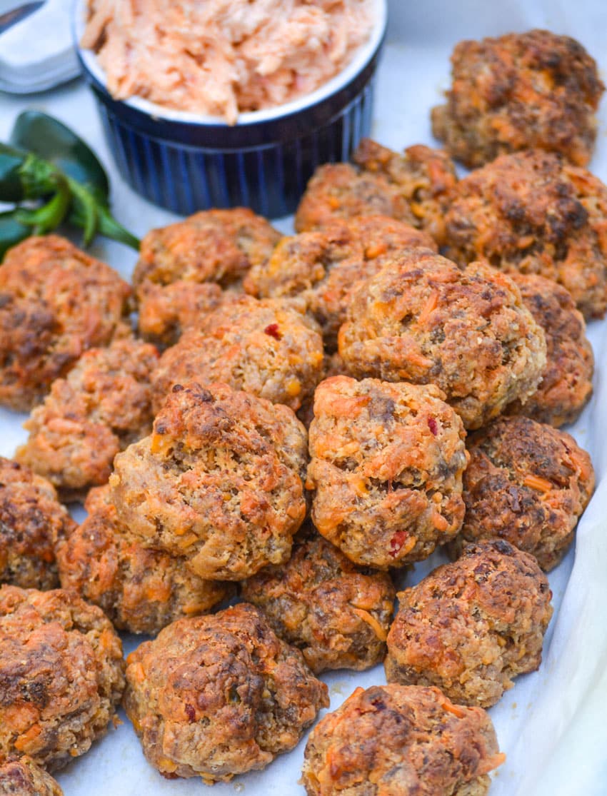 spicy pimento cheese sausage balls piled on a parchment paper lined platter
