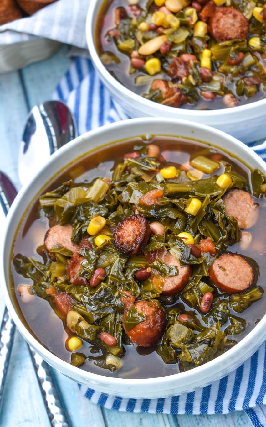 swamp soup in two white bowls with two silver spoons resting on the edge