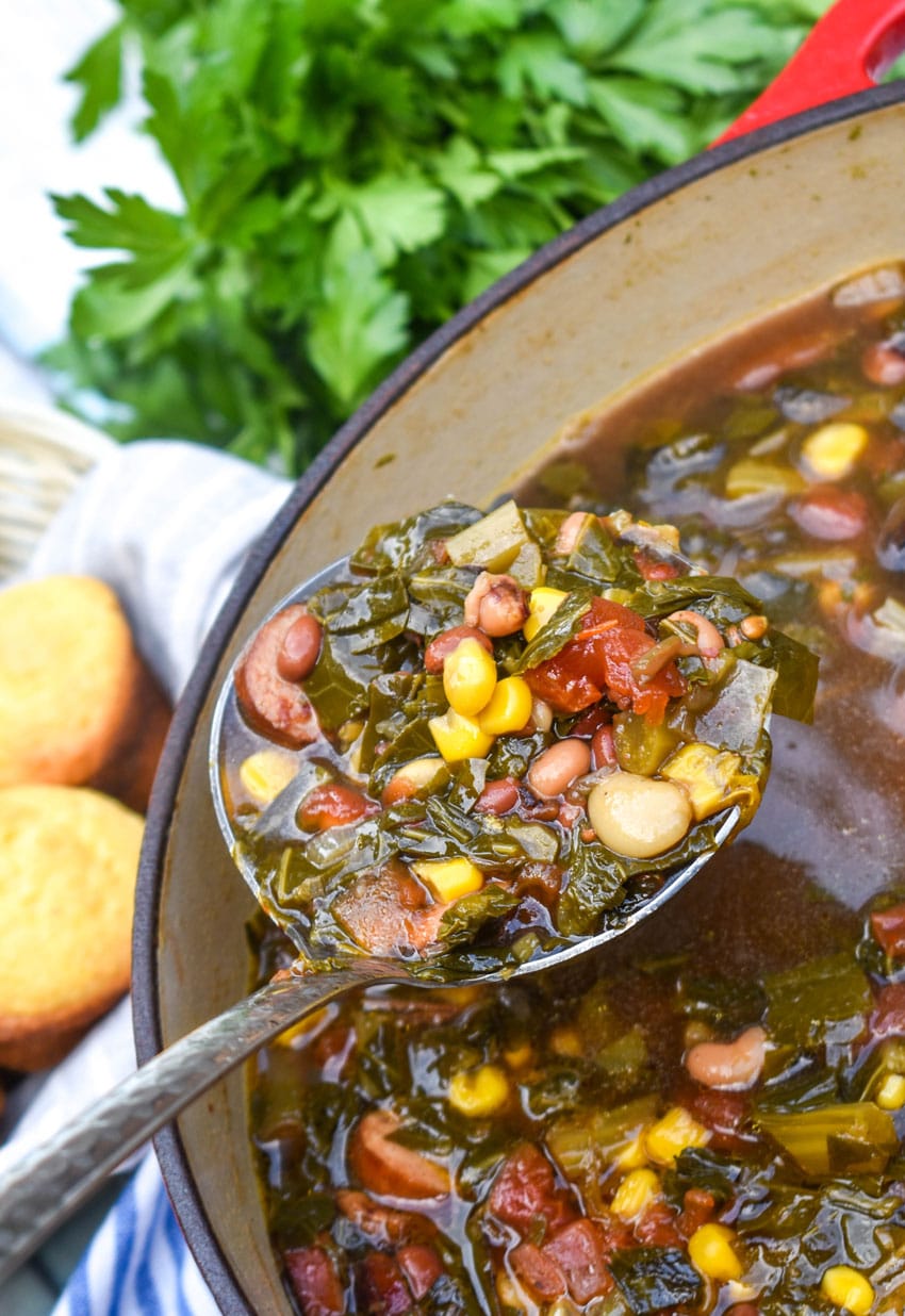a silver ladle scooping swamp soup out of a large red dutch oven