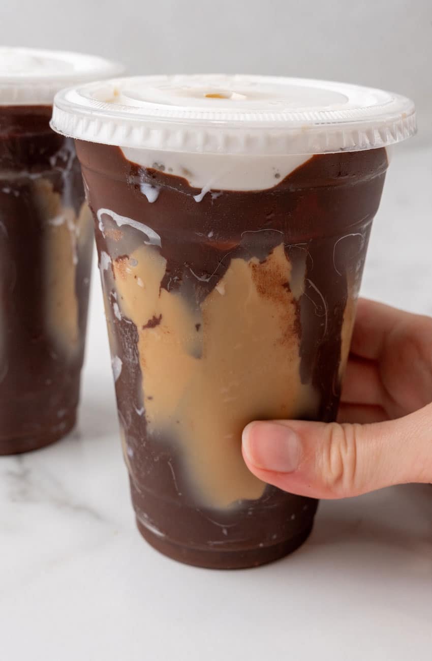 a hand holding a plastic cup of crackle coffee