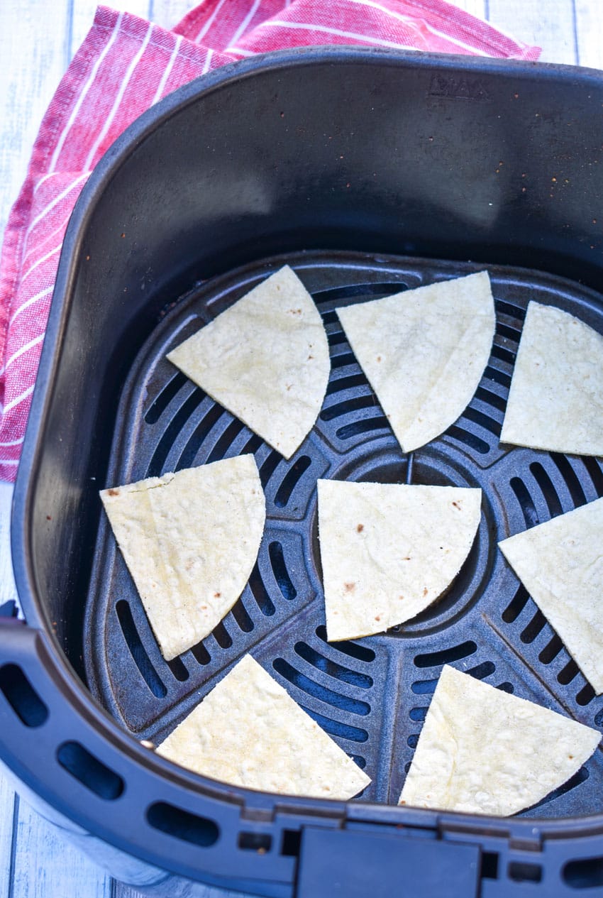 corn tortilla triangles in the basket of an air fryer