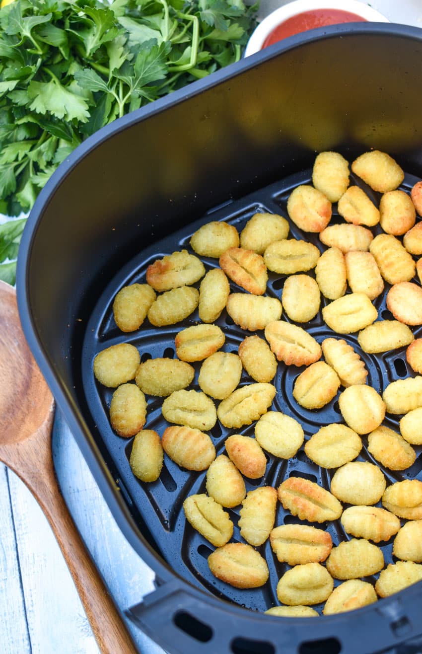 crispy cooked potato gnocchi in the basket of an air fryer