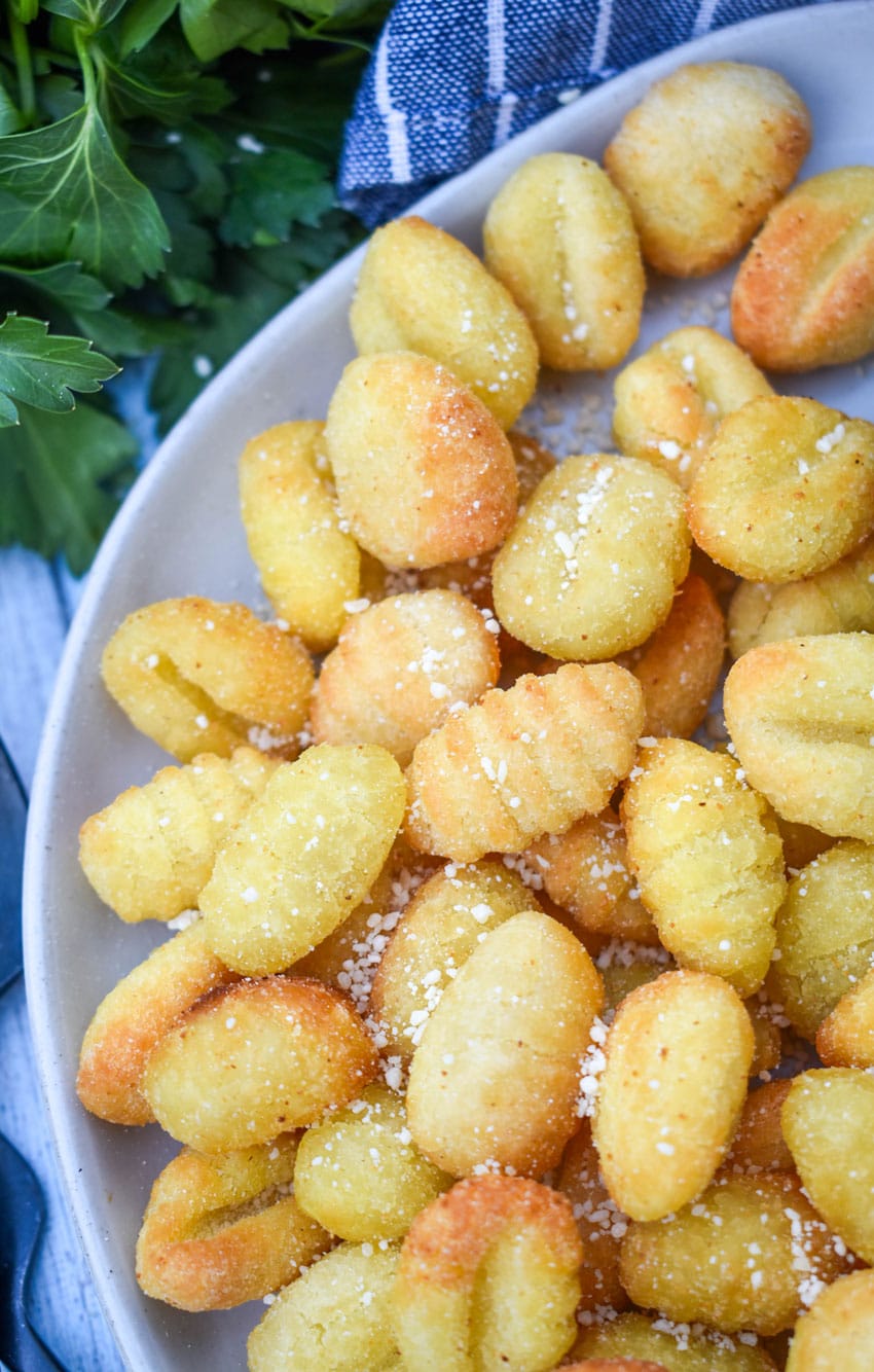 crispy air fryer gnocchi on a large white plate with a small bowl of marinara sauce on the side