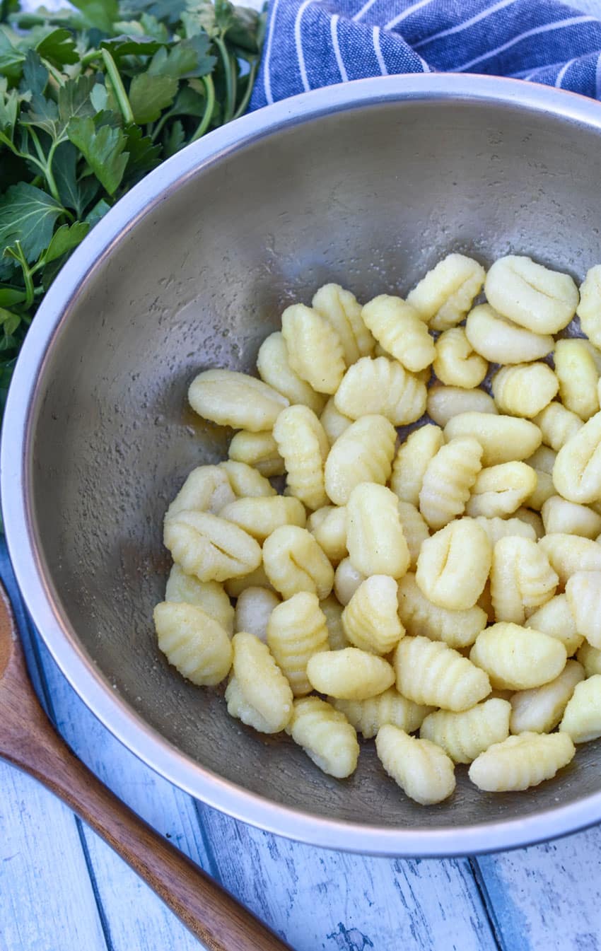potato gnocchi coated with olive oil in a metal mixing bowl